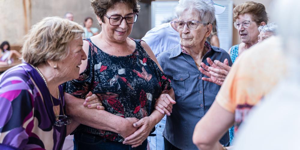 vrouw van middelbare leeftijd loopt arm in arm met twee oudere vrouwen