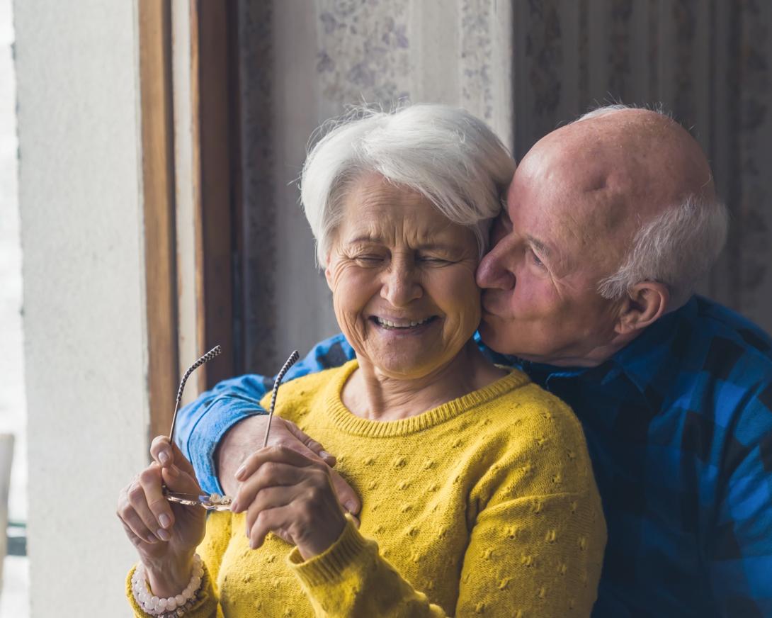 oudere man verrast zijn vrouw met kus in de hals