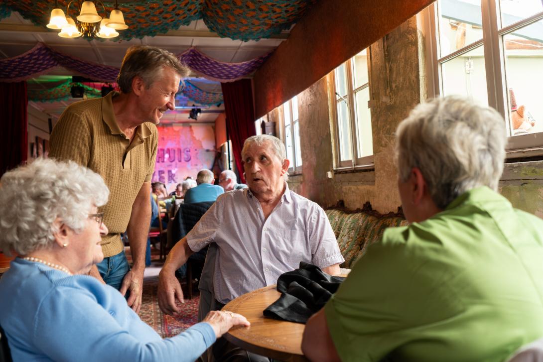 Groepje ouderen praten rond tafel